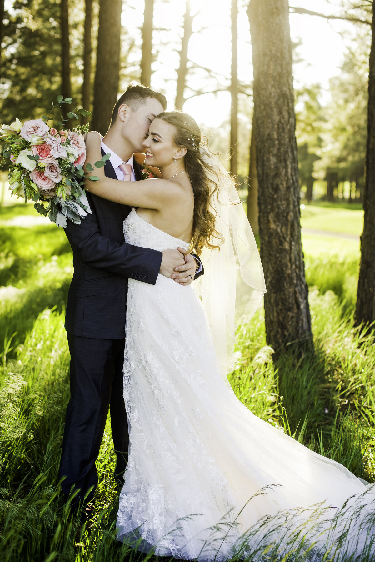 Bride and Groom holding each other kissing cheek Elephant Golf Course Williams Flagstaff wedding sunlight
