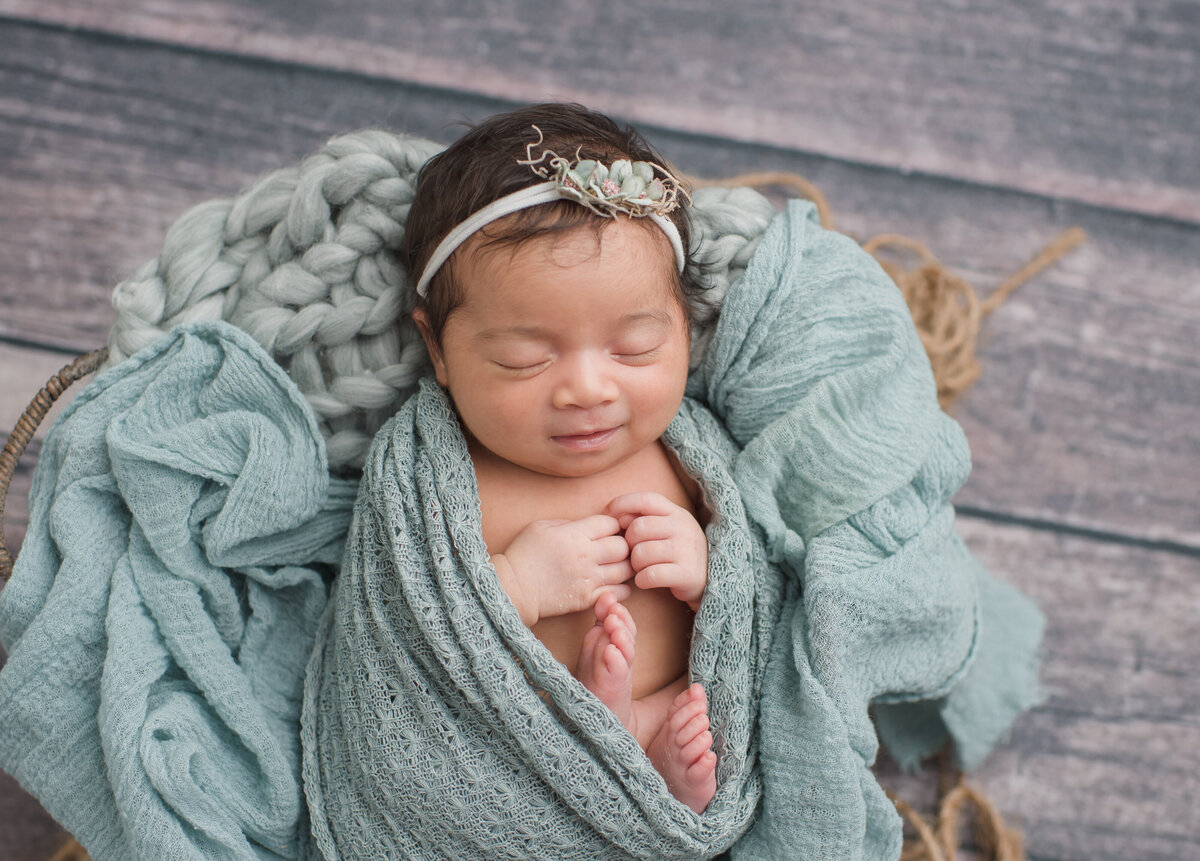 newborn wrapped in cyan blue blanket and posed