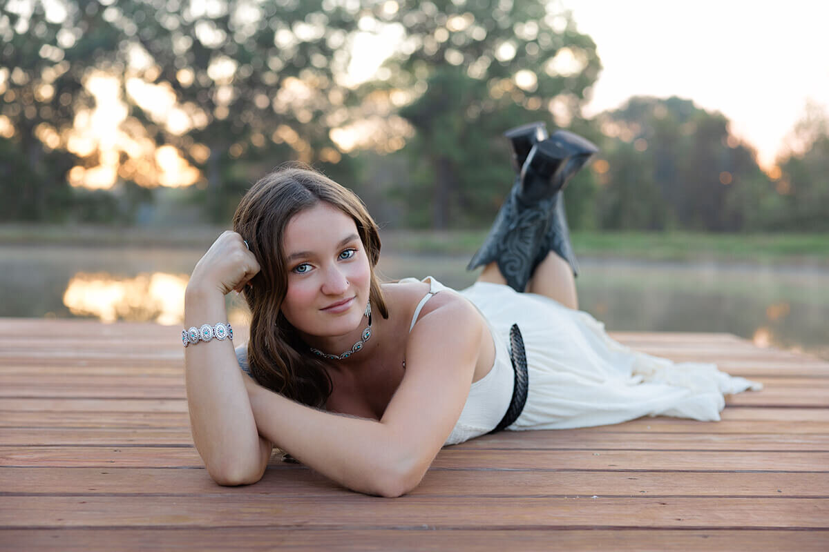 baby girl posed bum up on a white wooden bed in front of white backlit curtains.