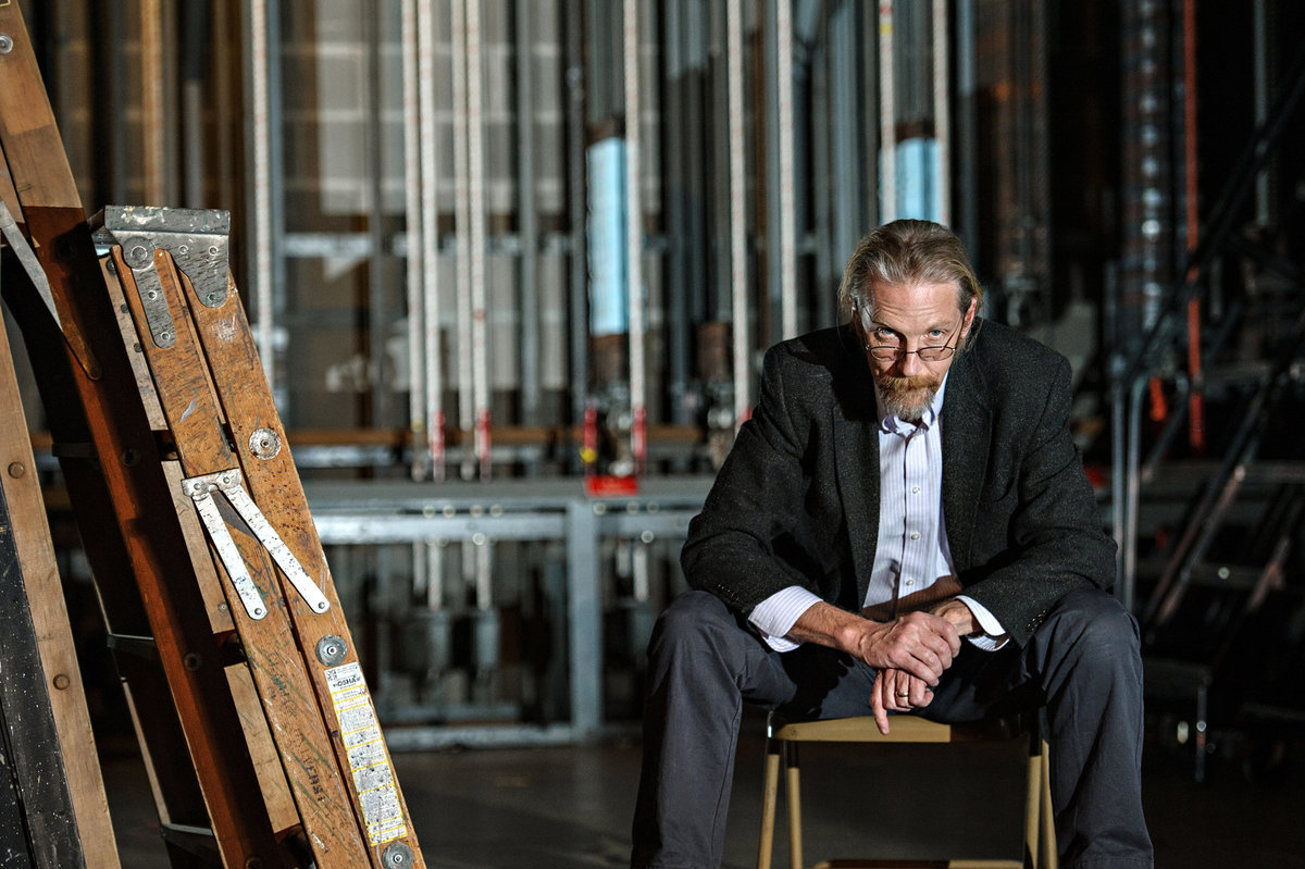 A drama professor sits back stage.