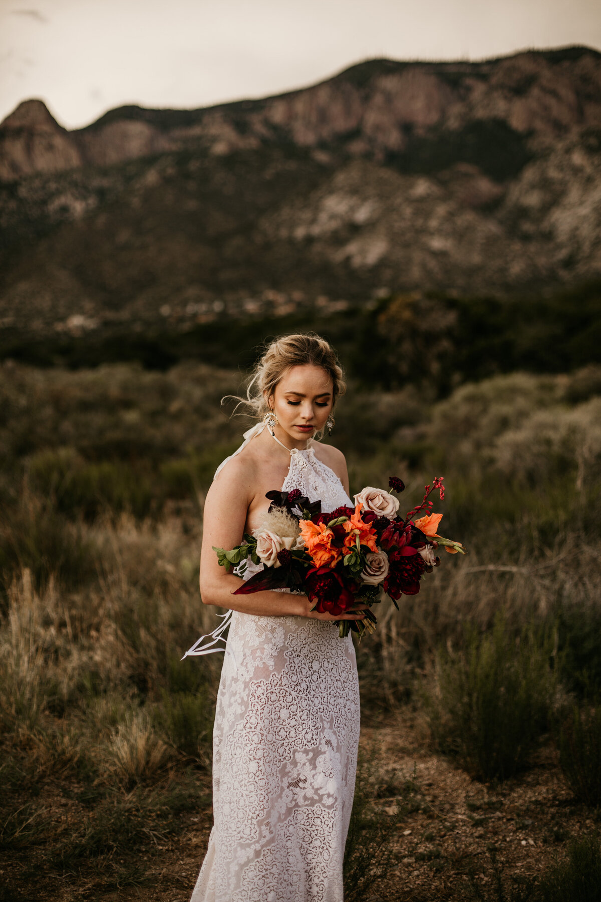 brind standing in fron of mountain with bouquet