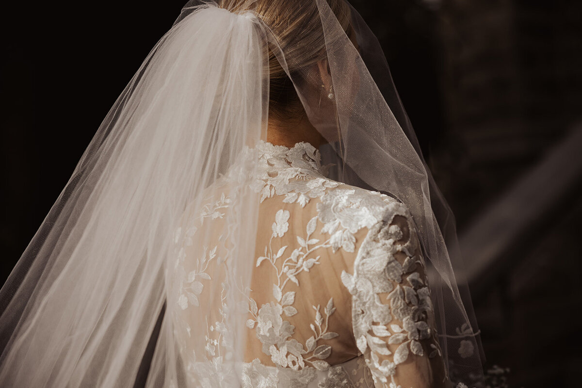 Bride's veiled back, lace gown, photo shoot.