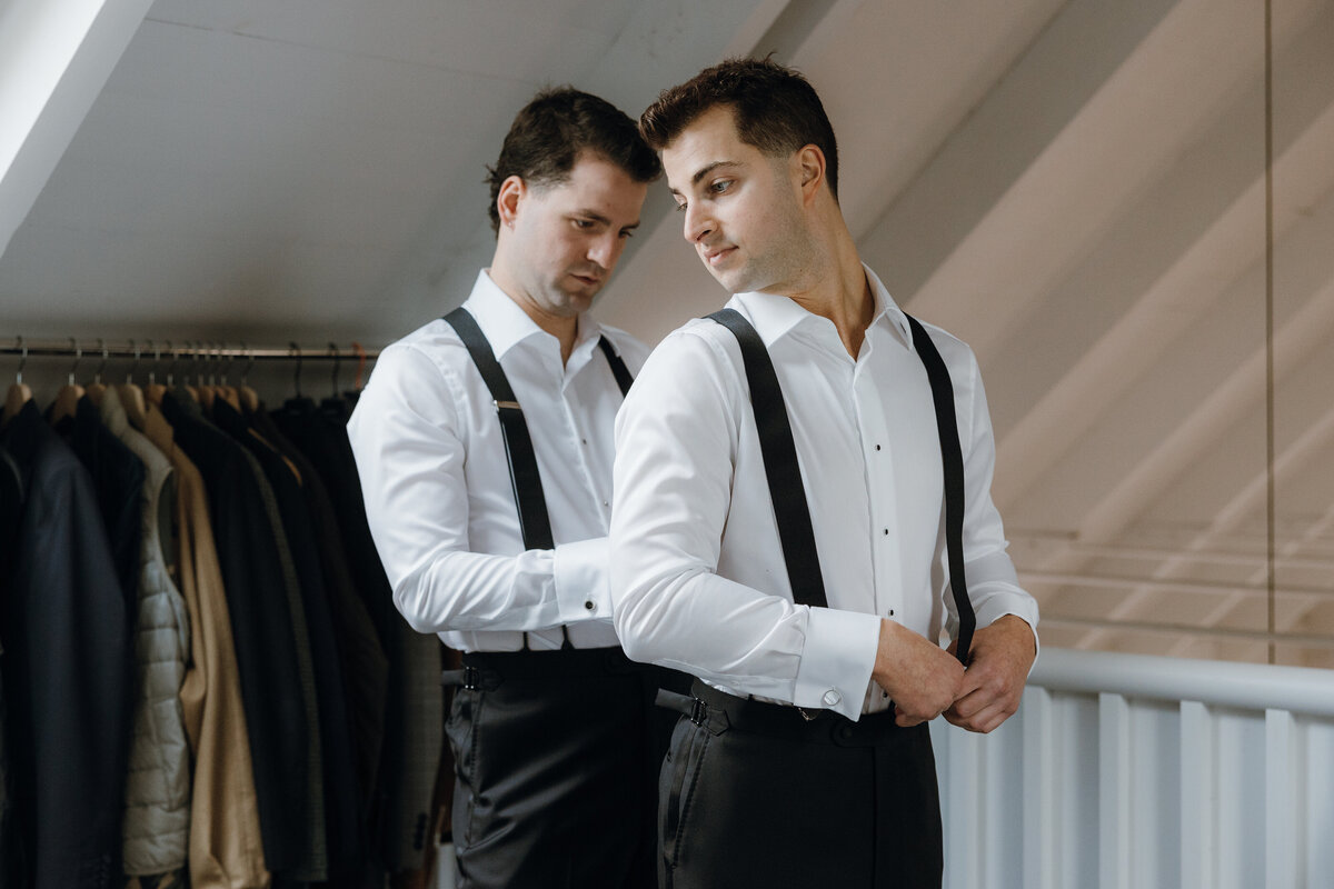 Groom giving his partner a hand, putting on suspenders.