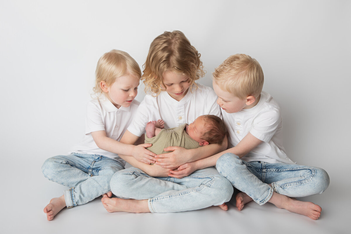 Four siblings studio newborn pose