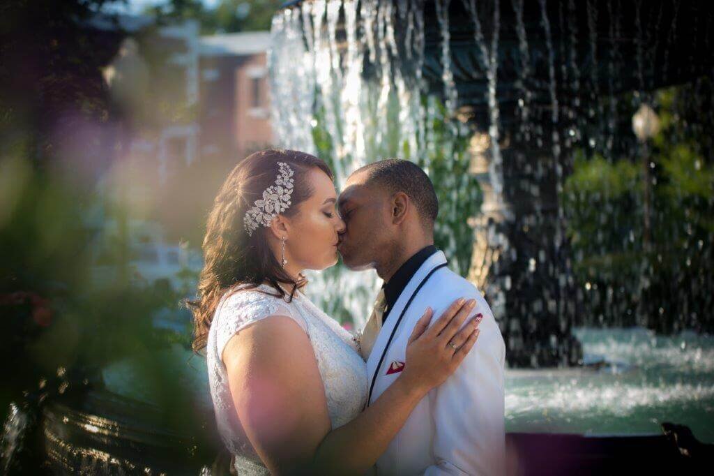 Bride and groom kiss in front of a fountain at Vizcaya in Sacramento.