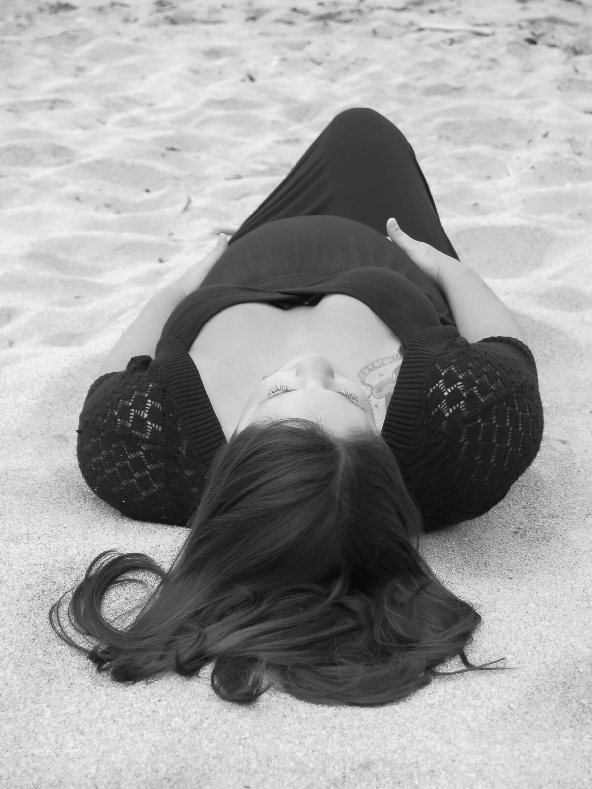 B&W photo of Pregnant woman laying on sandy beach