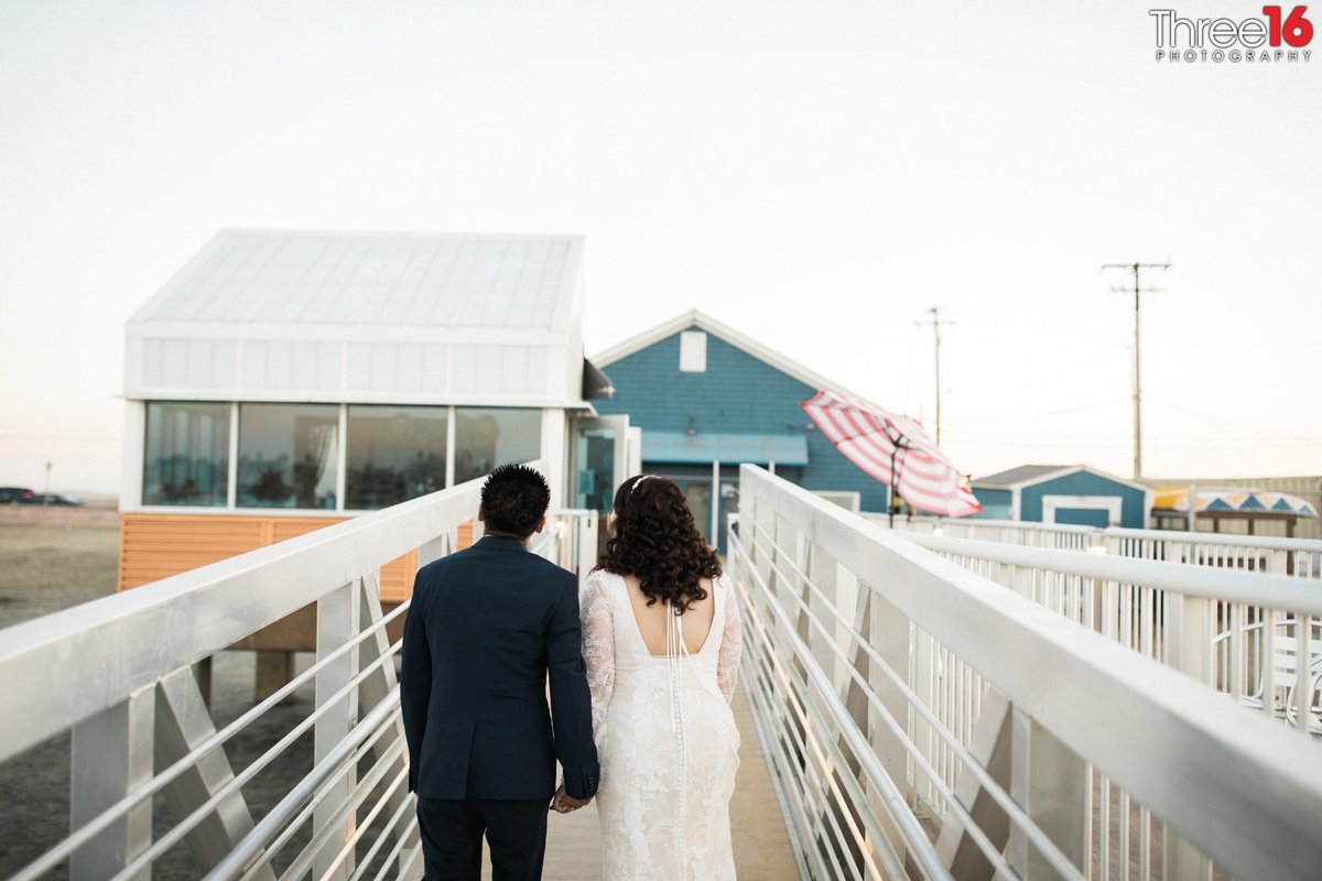 Bride and Groom walk away on the dock holding hands
