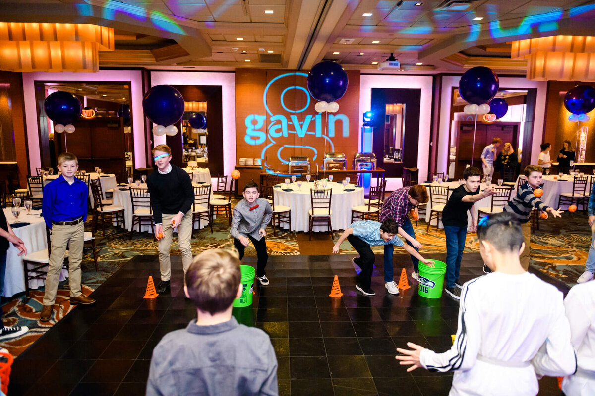 A group of teenage boys play a variety of party games on the dance floor during a mitzvah