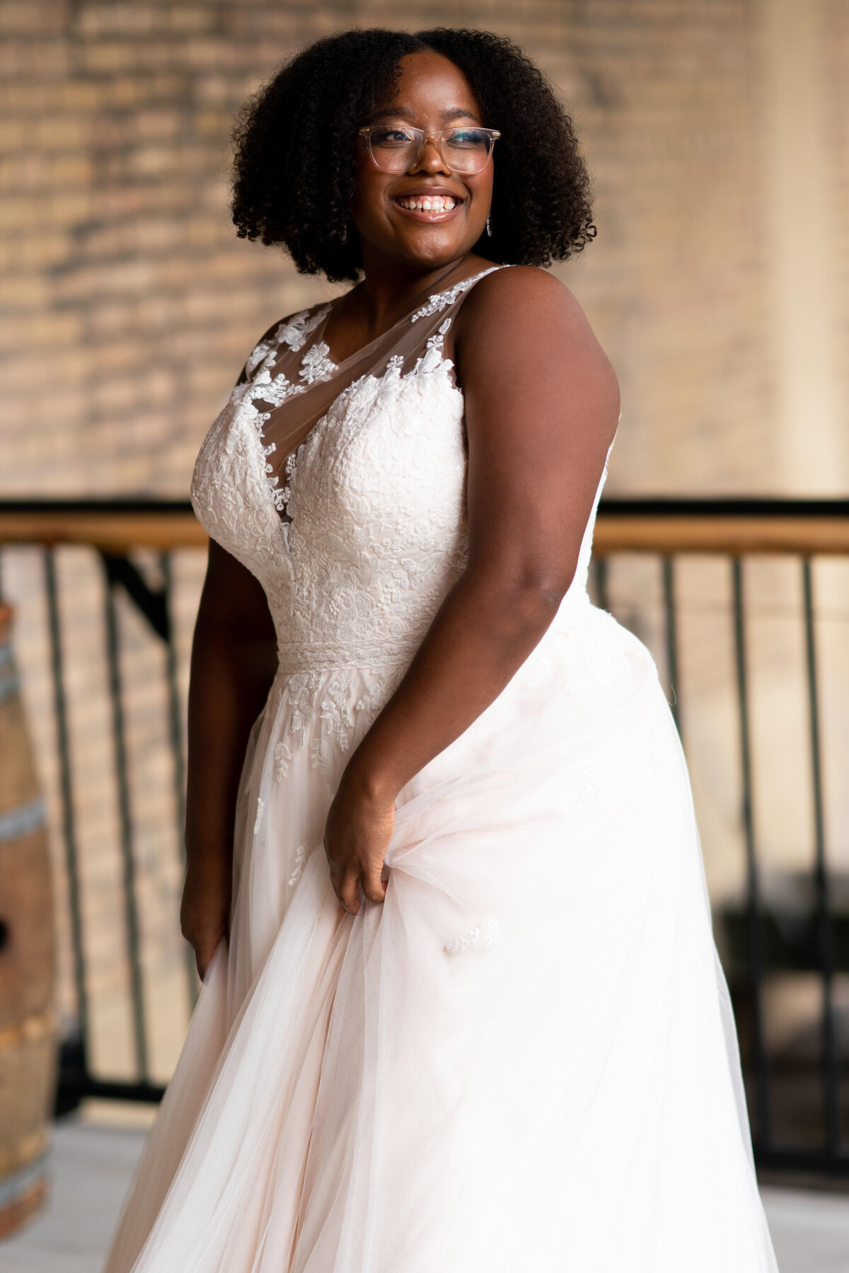 Black bride with glasses laughs wearing her wedding dress.