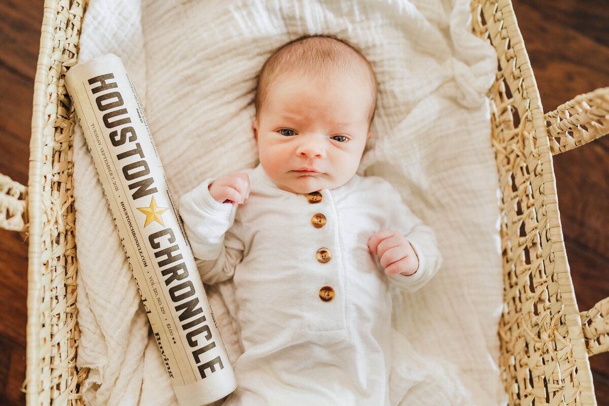 Newborn baby boy laying next to the Houston, TX Newspaper with the headlines from his date of birth.
