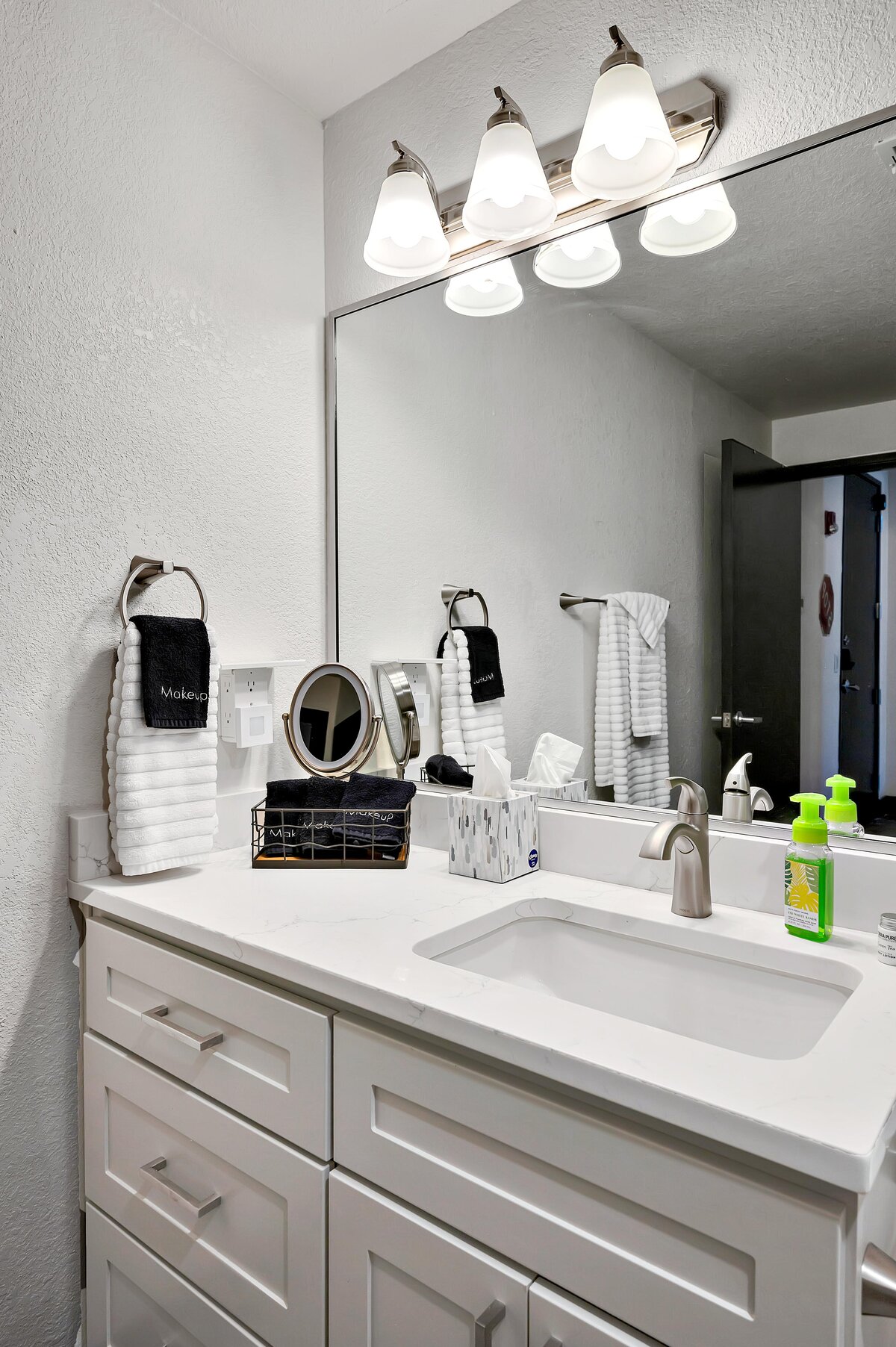 Bathroom vanity with large mirror in this one-bedroom, one-bathroom vintage industrial condo with Smart TV, free Wi-Fi, and washer/dryer located in downtown Waco, TX.