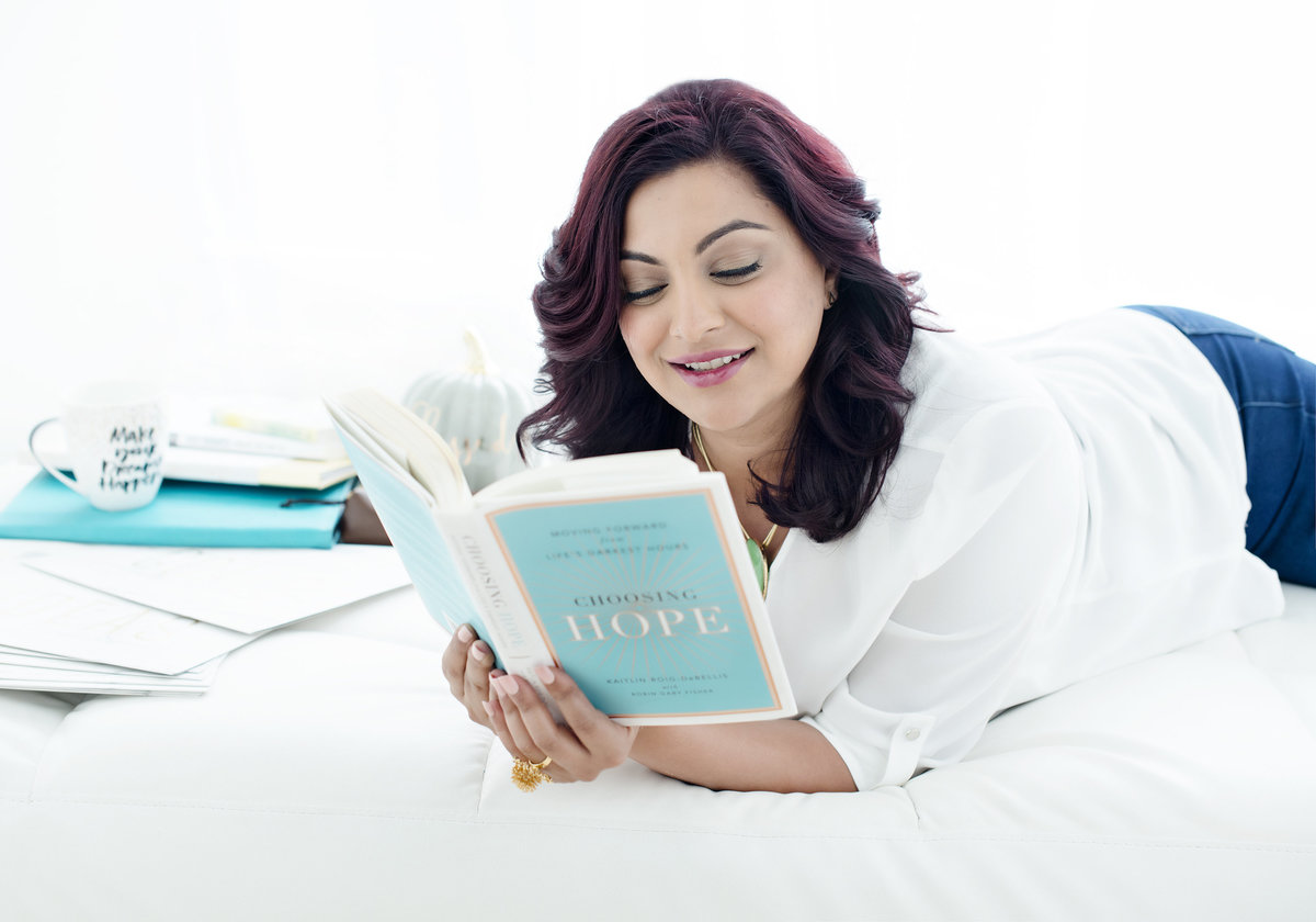 personal branding for  author reading book lying on her stomach on a couch happy and  bright in studio by  BRANDING Puja misra best photographer in mississauga- BRANDING PHOTOGRAPHER , MARKETING STRATEGY