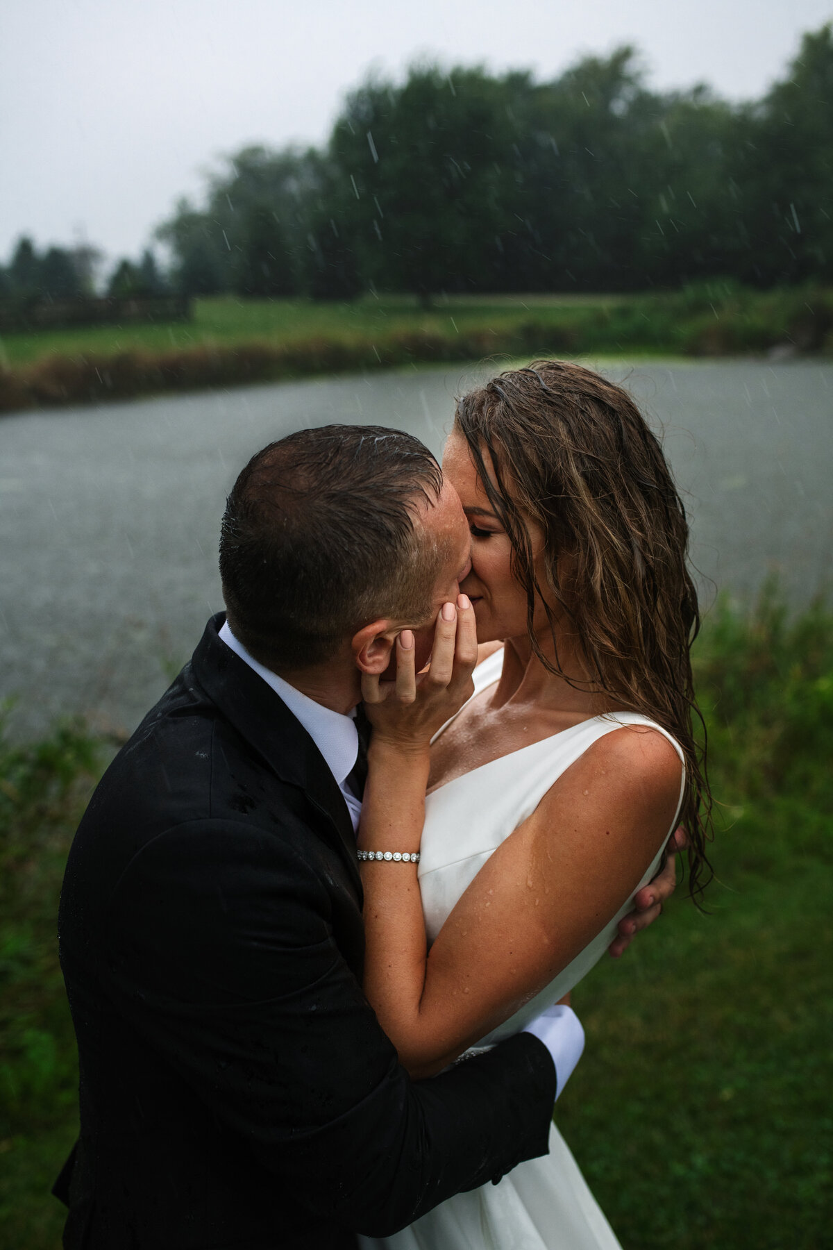 newlyweds kissing in the rain