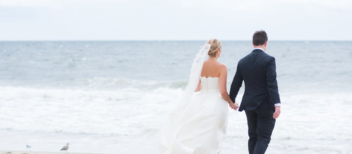 Bride and Groom walking on the Beach on a Windy Day at Spring Lake Bath and Tennis Club in Spring Lake, New Jersey Photo