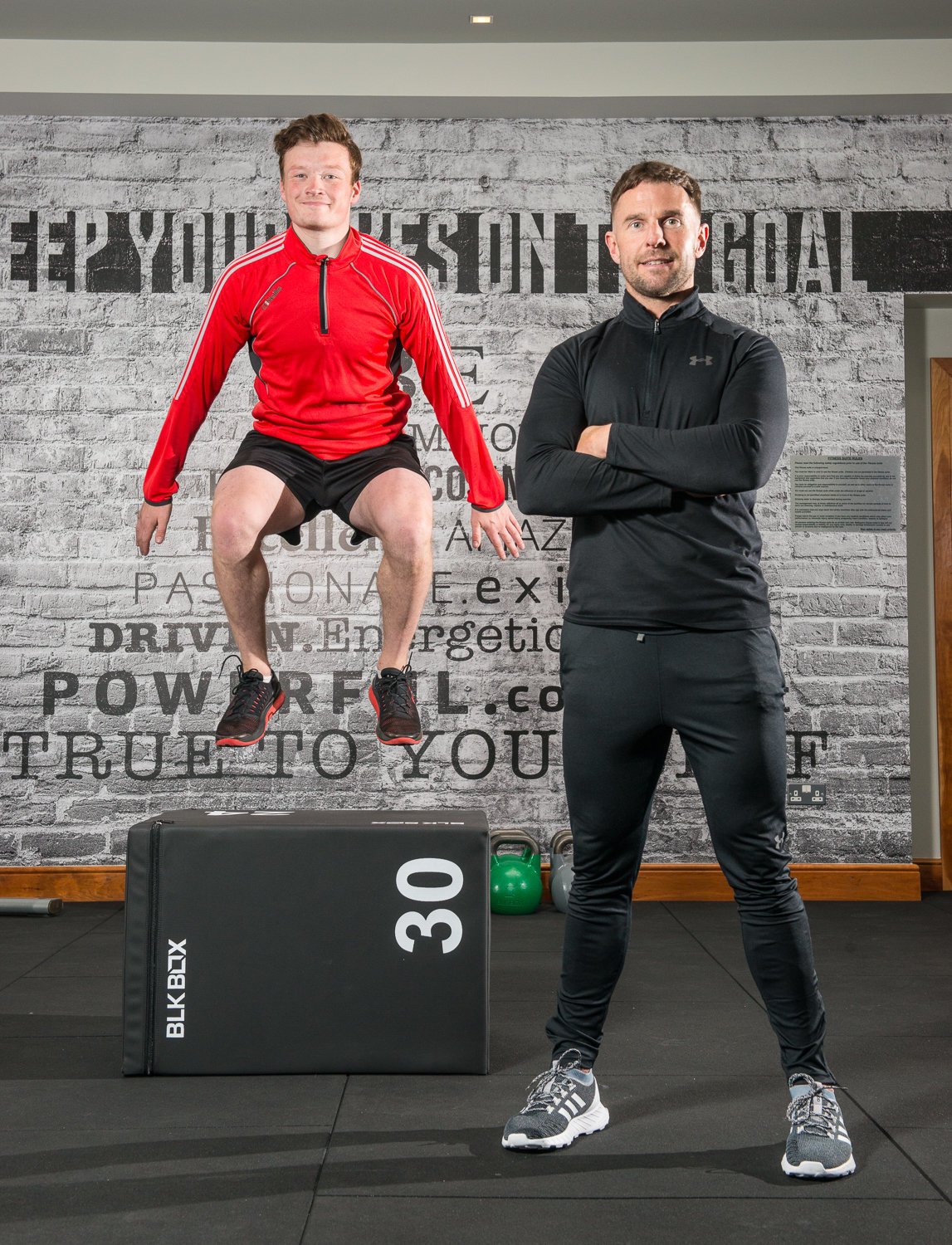 photo in gym with client jumping and fitness instructor