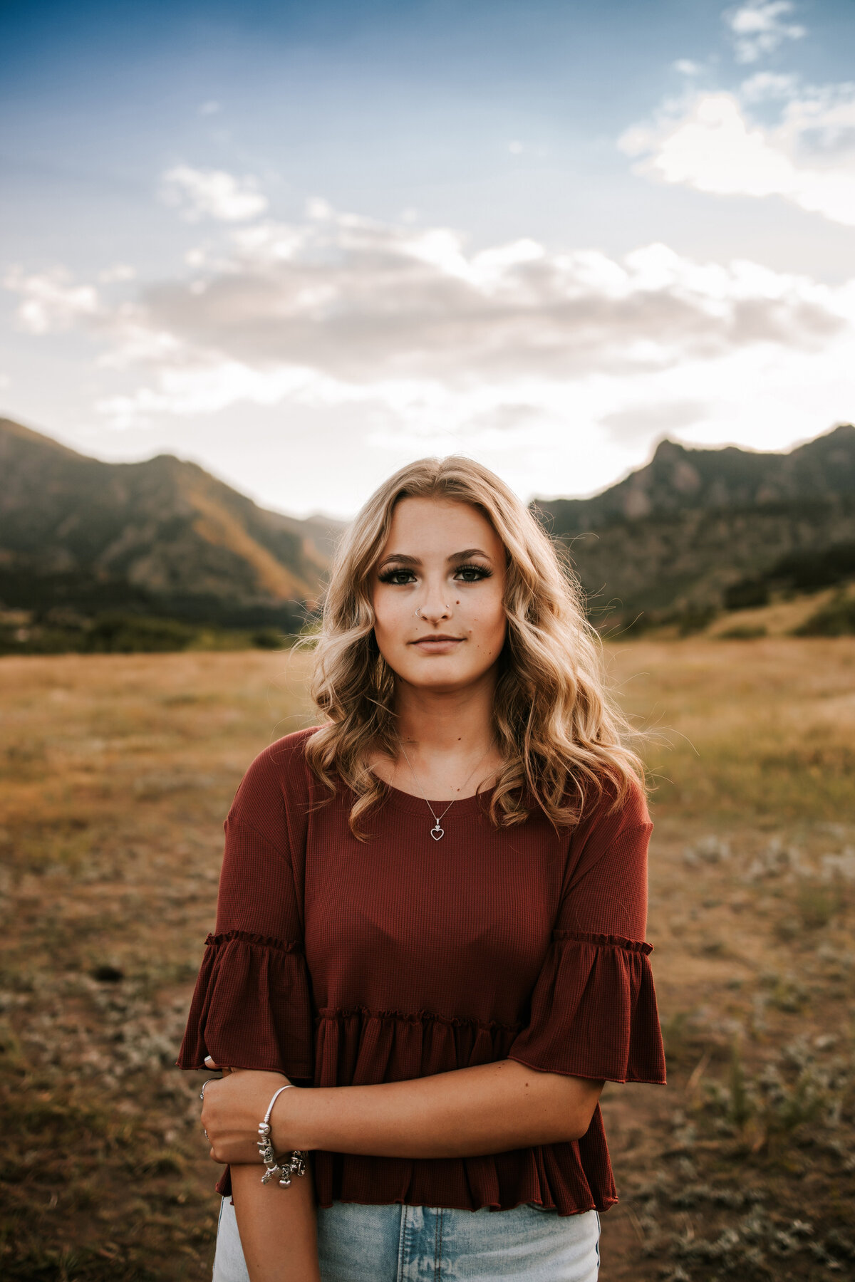 senior girl stands in large open field in boulder colorado for senior photos