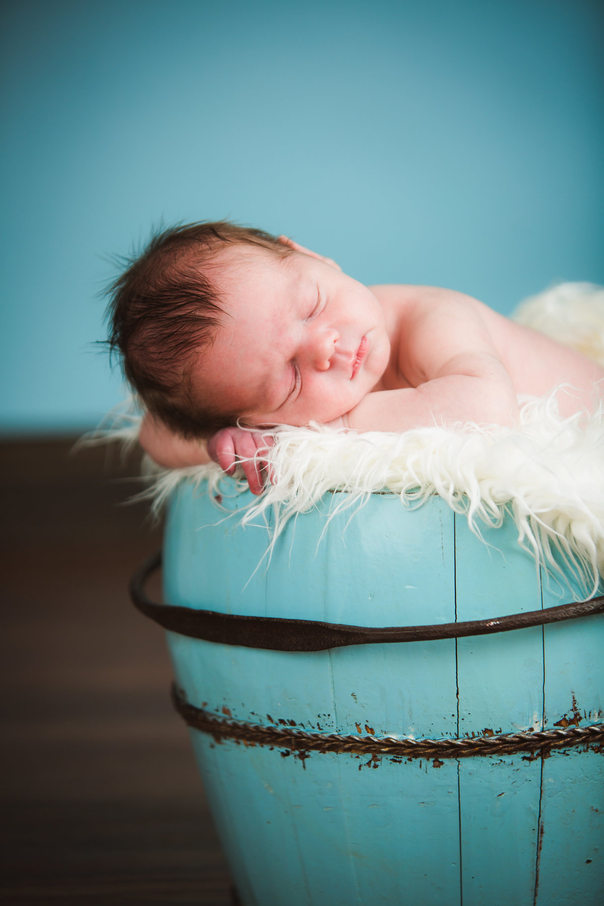 Sleepy newborn baby in antique bucket