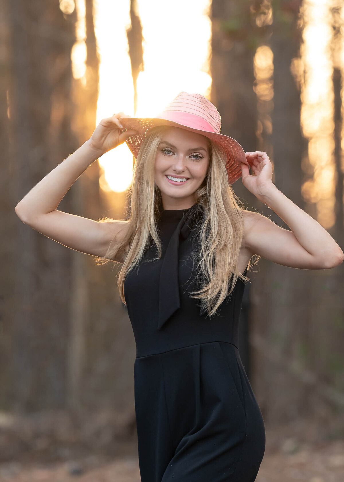 teenager smiling and looking at the camera holding her pink hat on her senior photo session by Elizabeth Klusmann Atlanta photographer