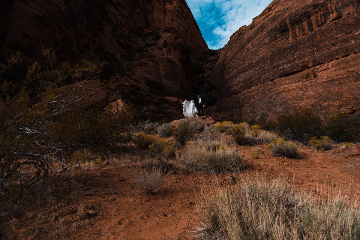 An eloping couple poses in the red rock canyons of Southern Utah as she plays with her wedding gown