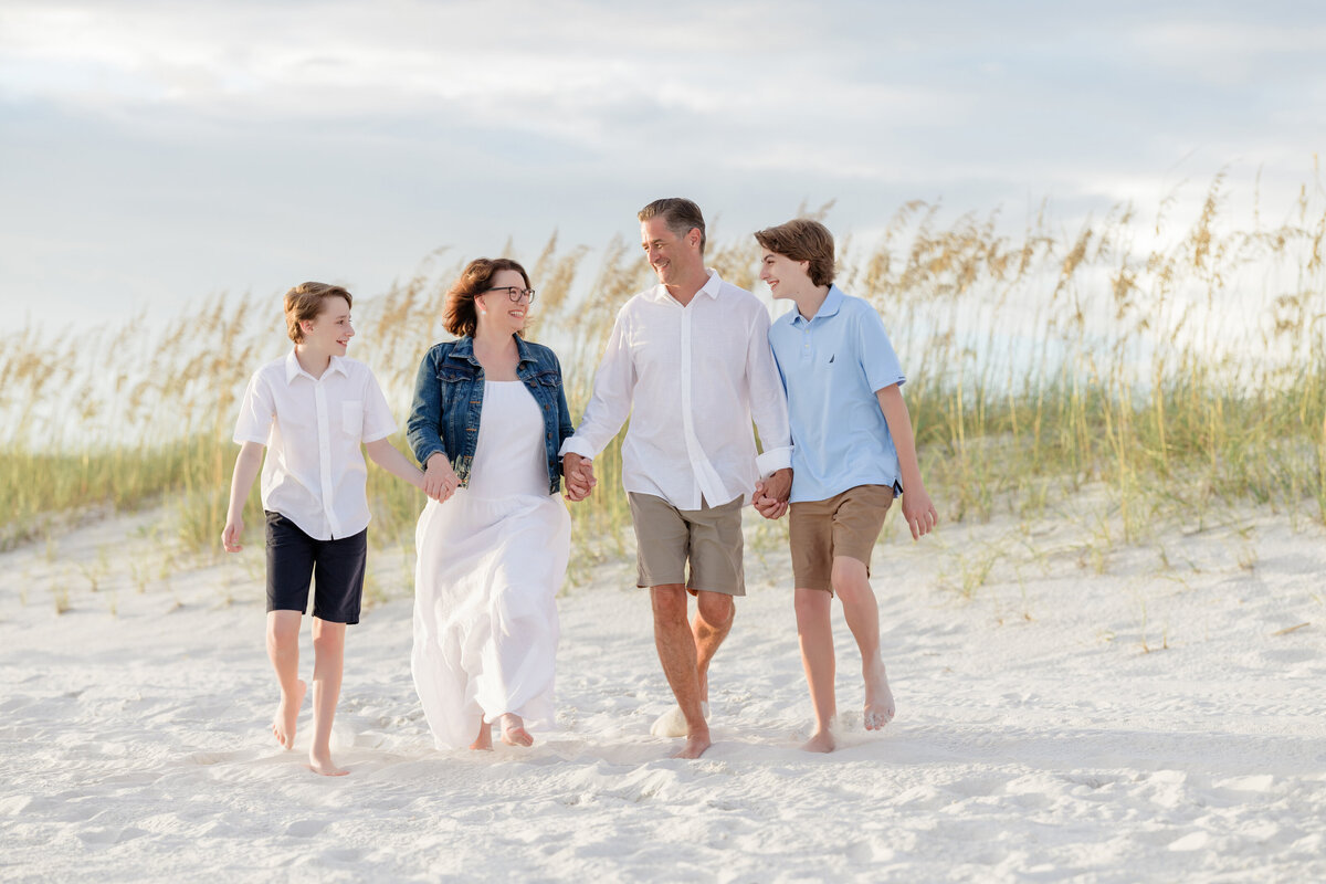 A family holding hands and walking in white sand