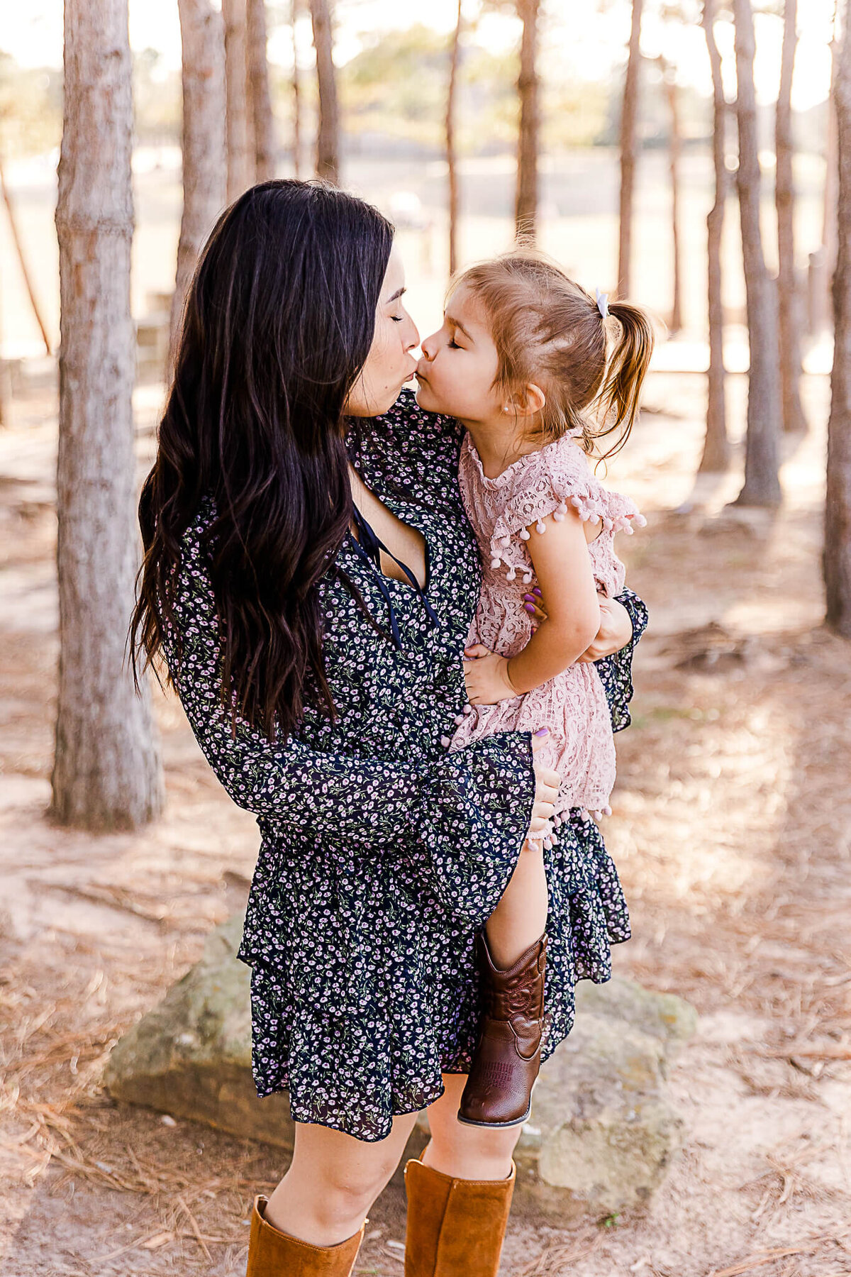 Mom holding and kissing daughter