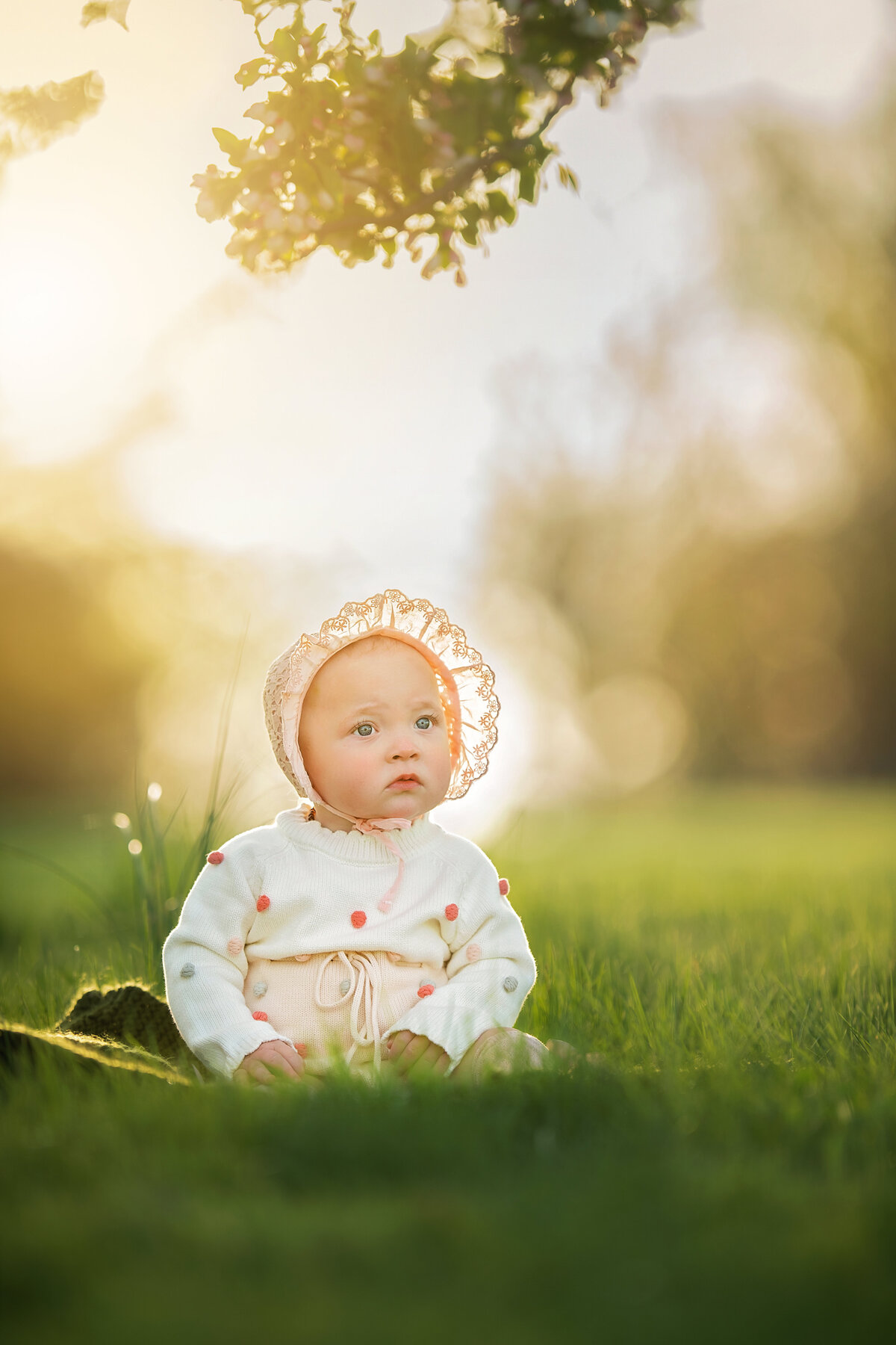 Baby with cute bonnet glowing in golden hour light in the springtime