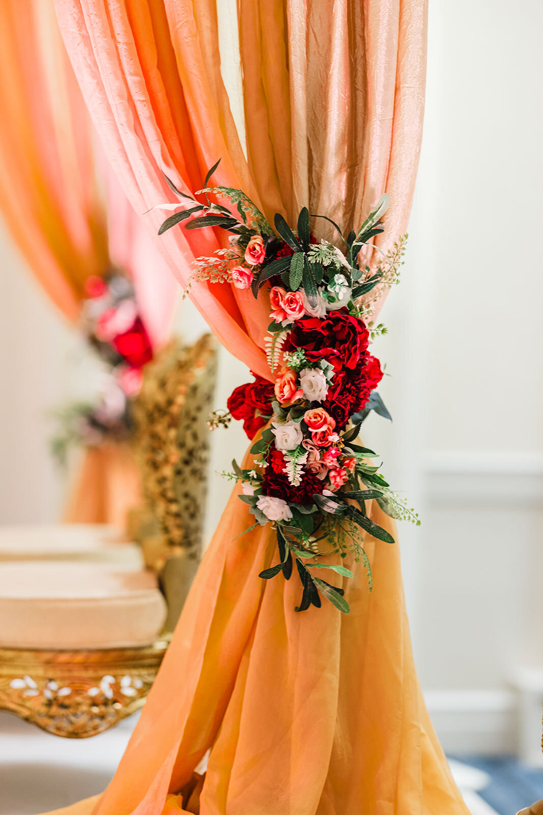 A decorative floral arrangement with red, white, and green flowers tied to a peach-colored fabric.