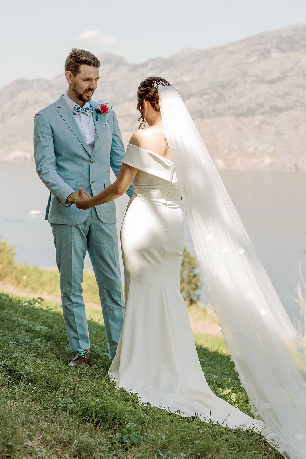 Groom in light blue suit holds his bride's hands.