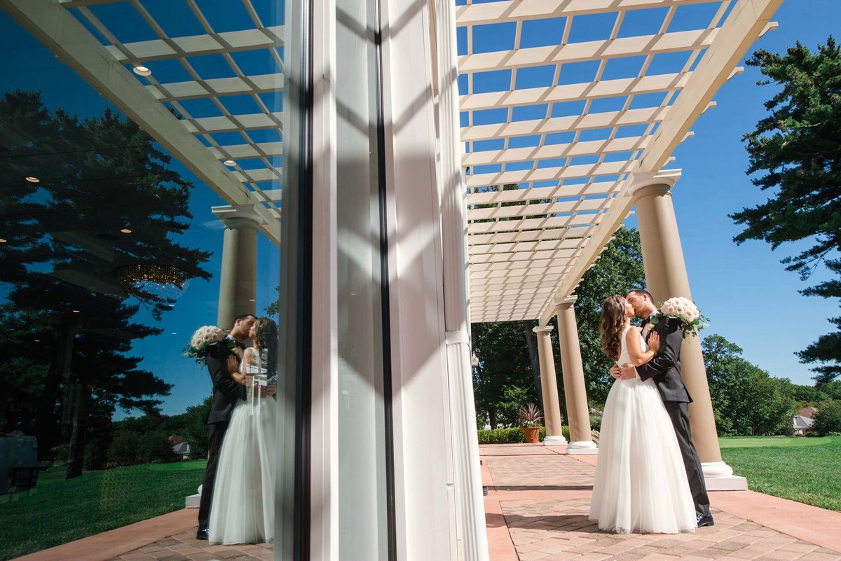 Bride and groom kissing on the side of the outdoor reception area at Stonebridge Country Club