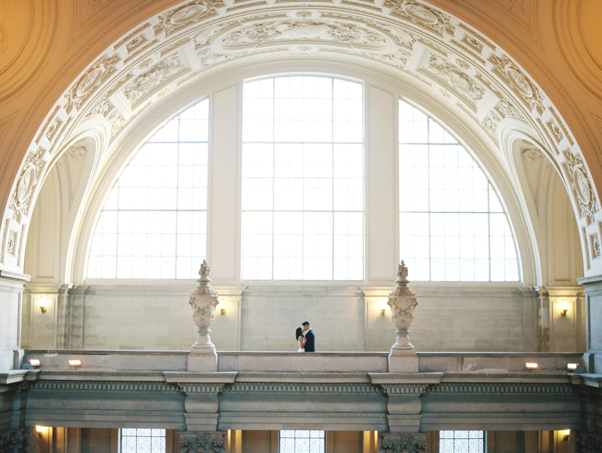 Bride and groom kissing in front of window photographed by Chicago editorial wedding photographer Arielle Peters