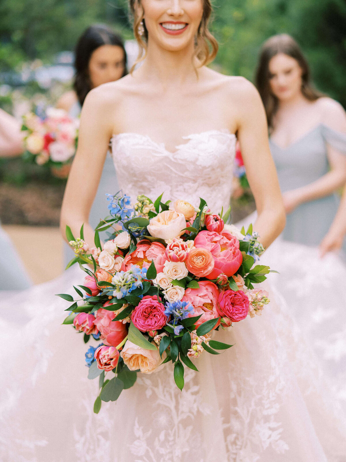 Bride smiles wearing her Monique Lhuillier wedding dress and holding colorful bouquet
