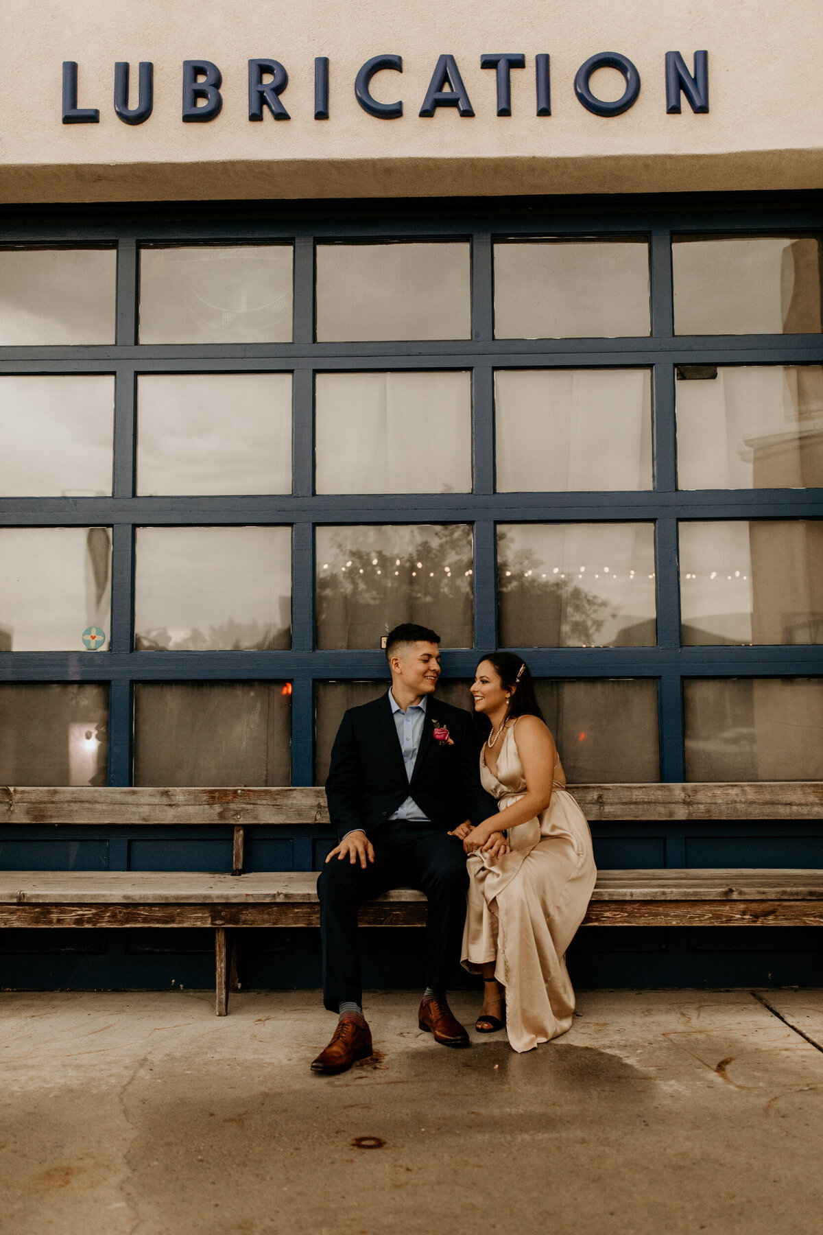 bride and groom sitting together at an abandoned  mechanic shop
