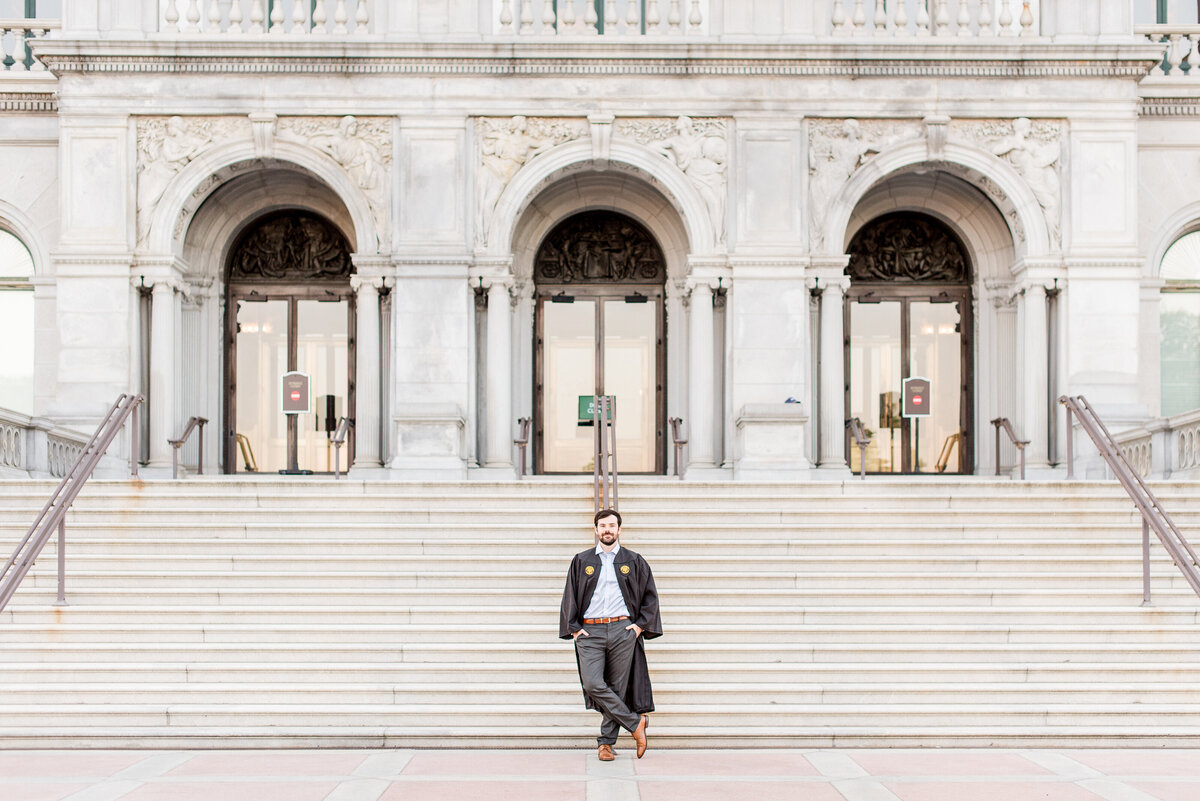 male grad standing on marble building