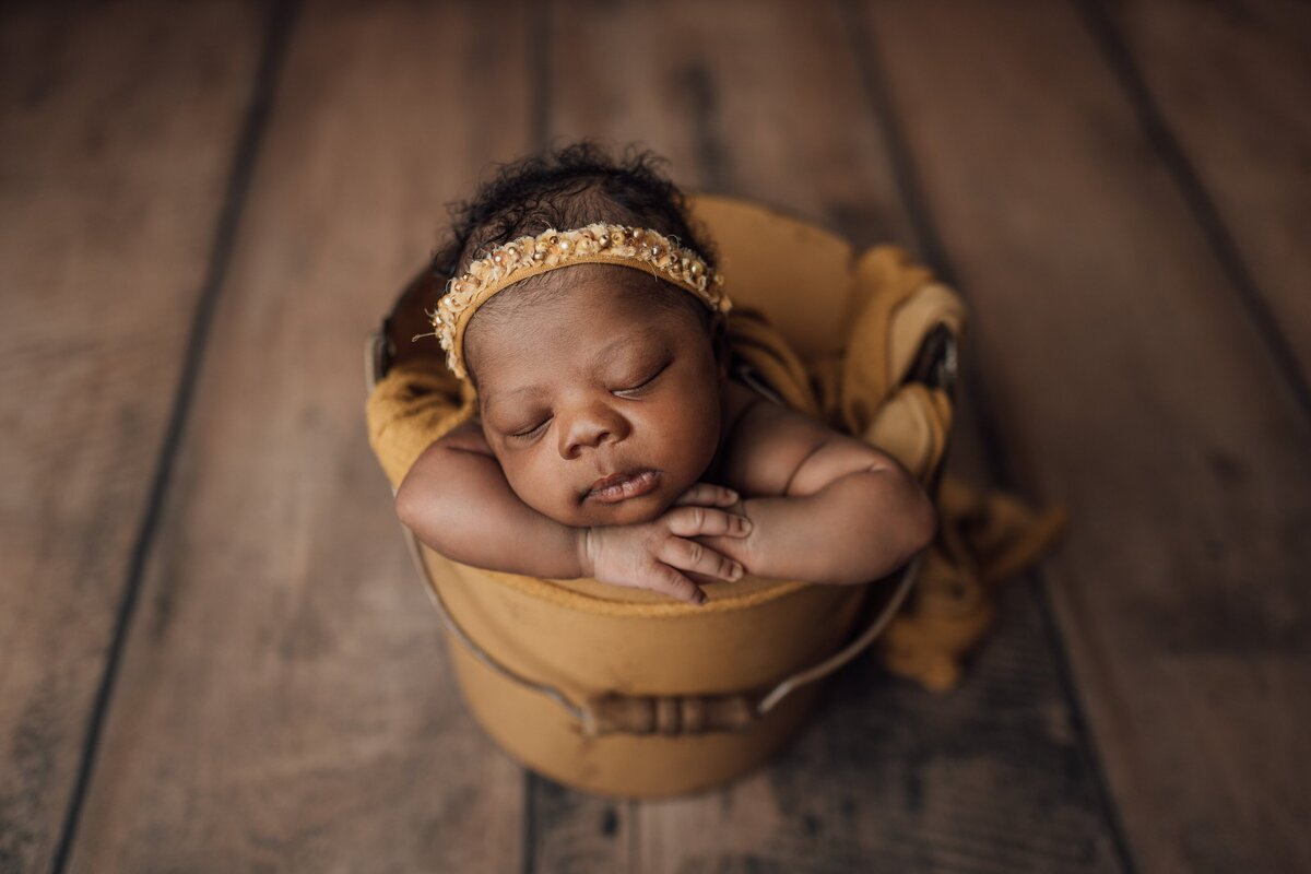 baby girl poses in bucket for photo session in tampa