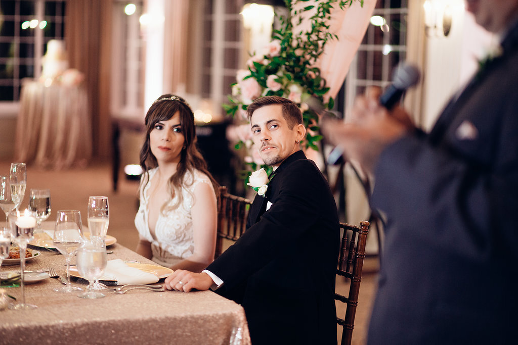 Wedding Photograph Of Bride And Groom Looking At The Man in Gray Suit Speaking In Microphone Los Angeles