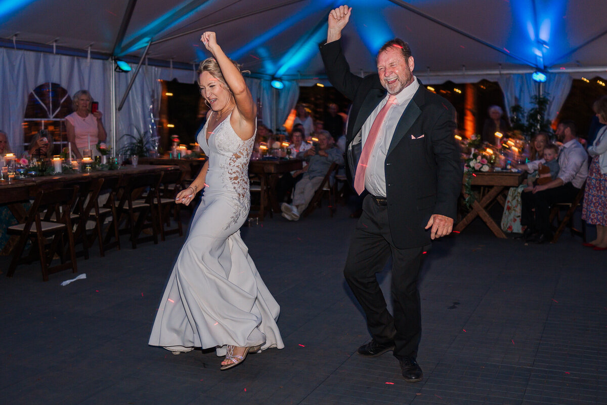 A fun father daughter dance during the bride's wedding reception under neon lights