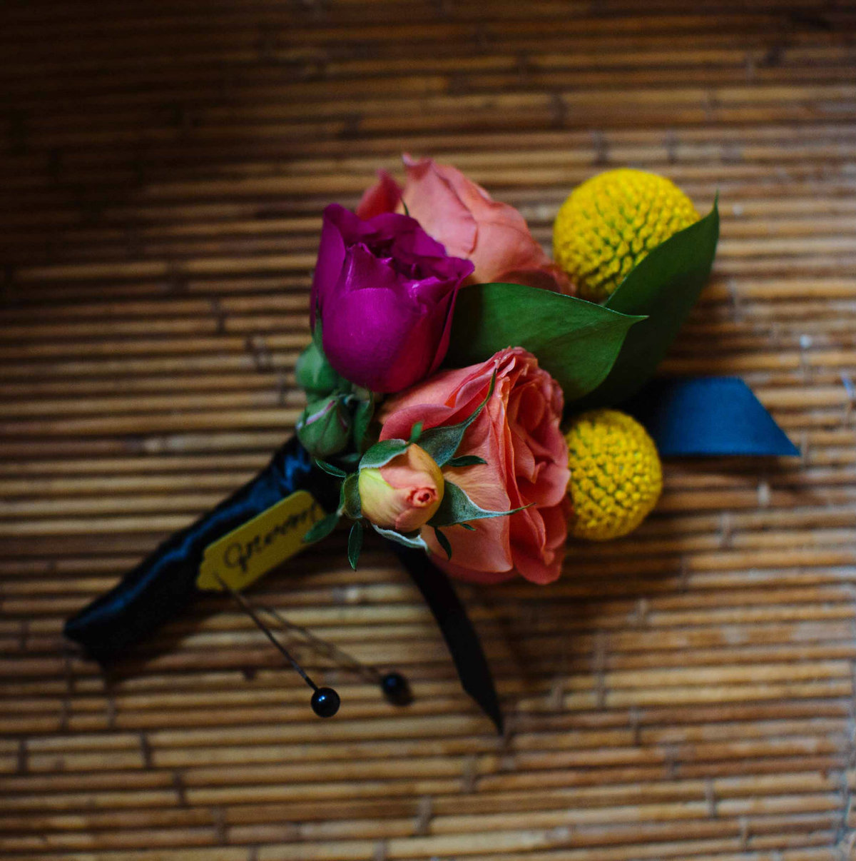Bright grooms boutonniere with roses and billy balls.