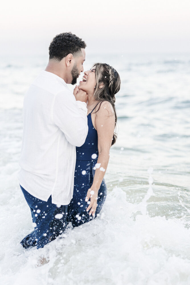 man and woman about to kiss while standing in the ocean