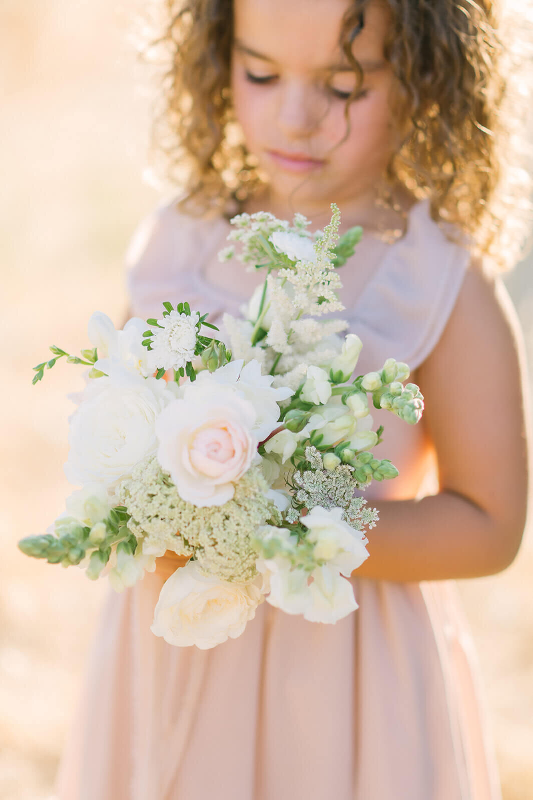 flower girl looking down at floral bouquet
