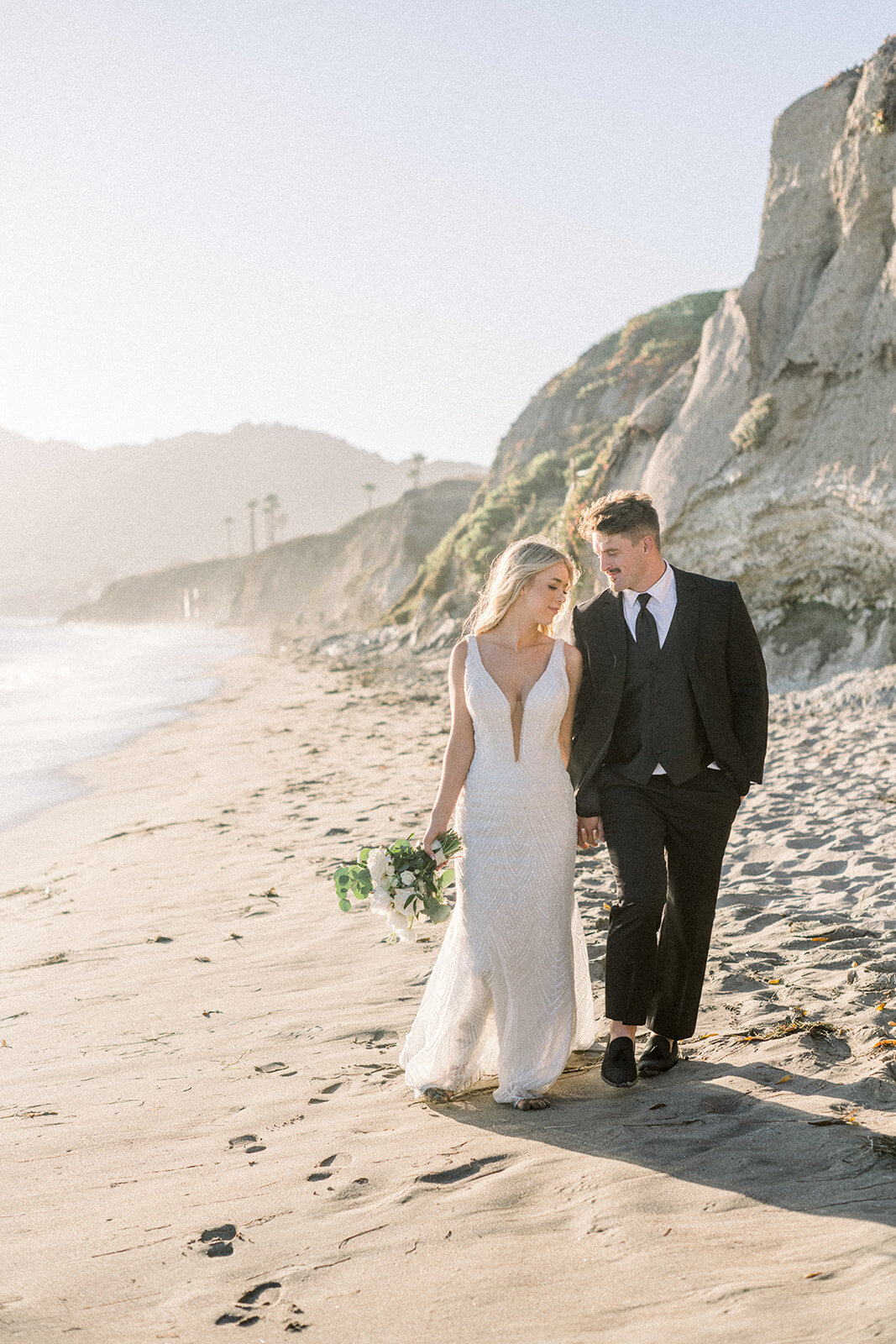 Bride and groom the beach dip during golden hour at Dolphin Bay Resort in Pismo Beach, CA