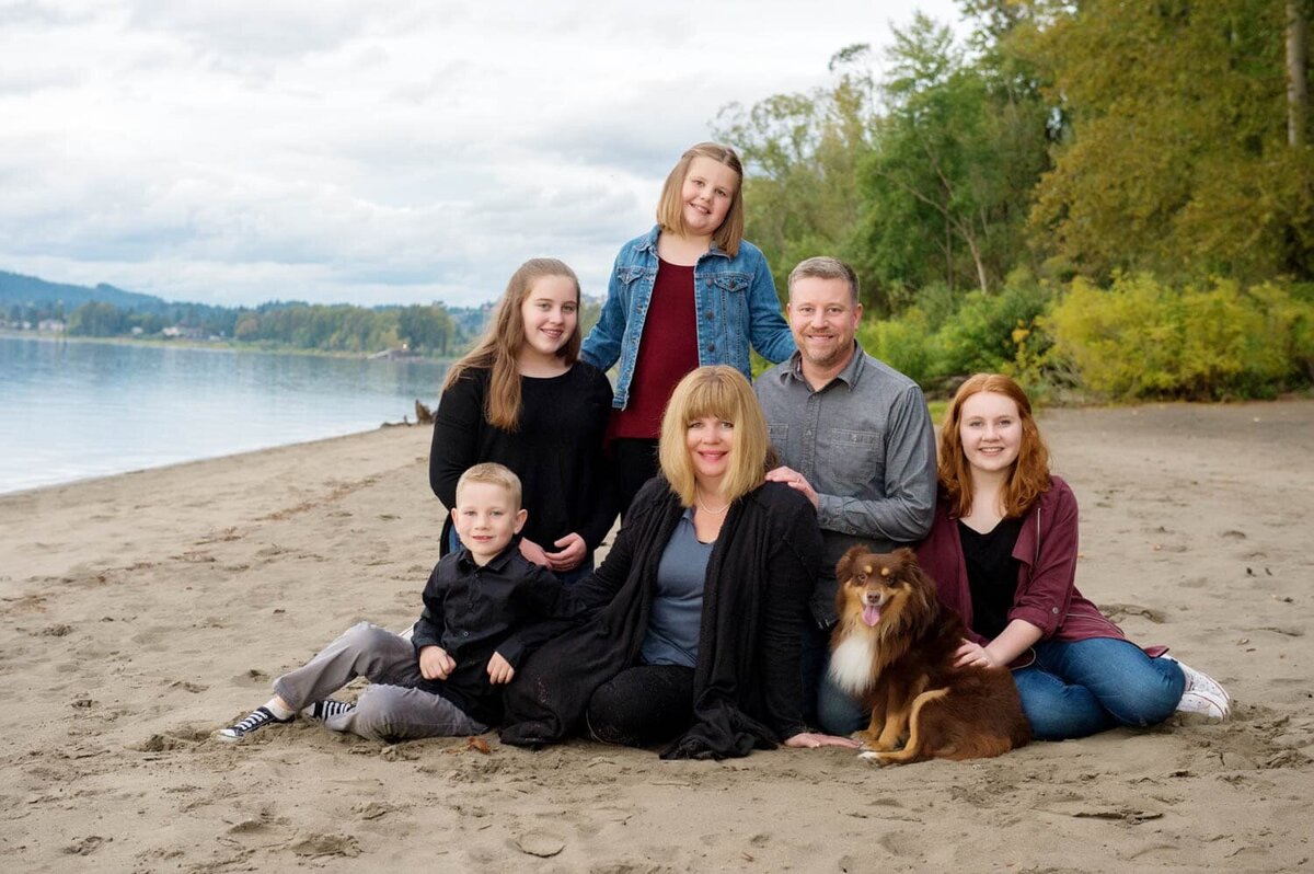 Family photo of mom and dad,  3 daughters and one son,  and their dog sitting on the beach at Vancouver Lake.