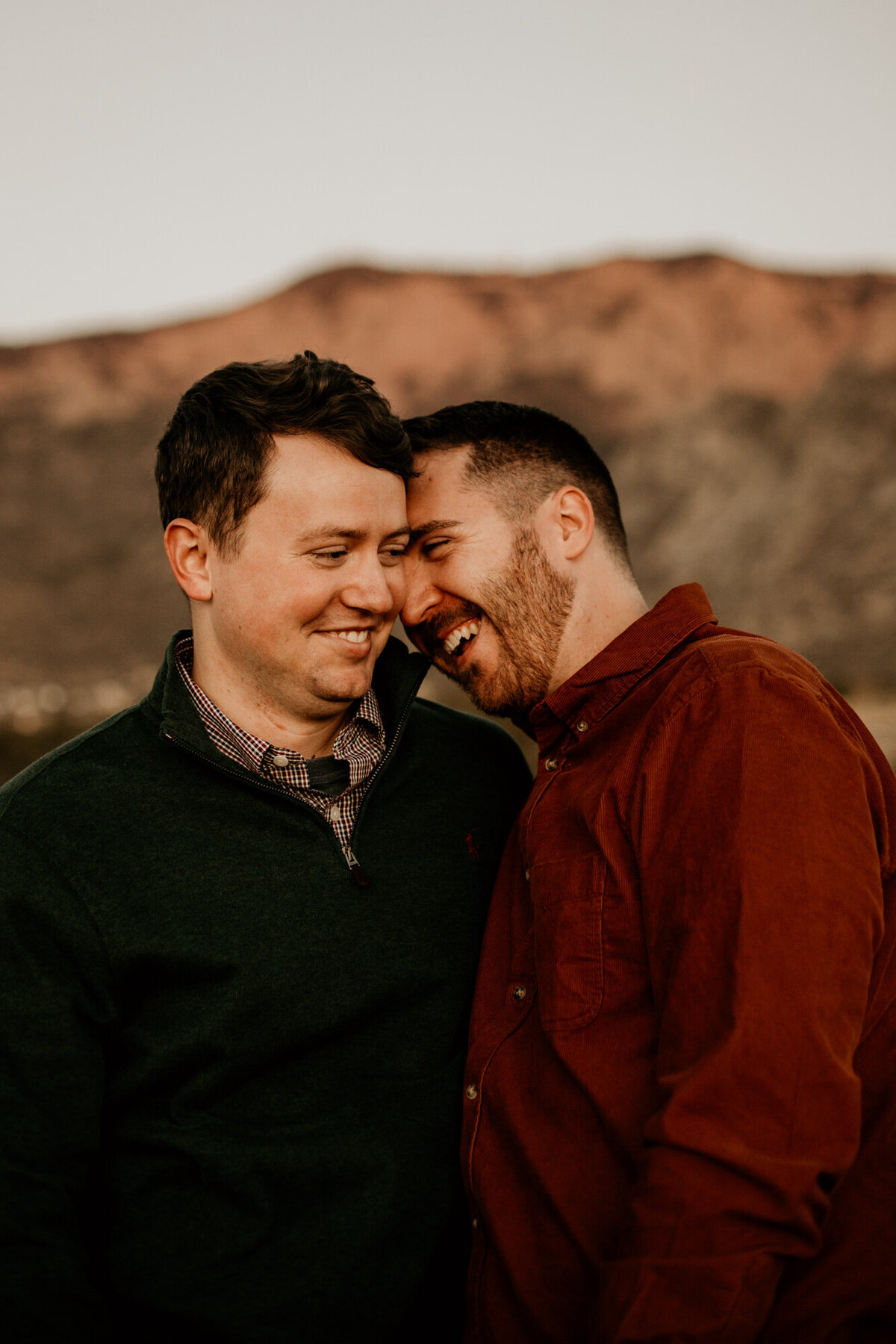 same sex engaged couple laughing with their heads together