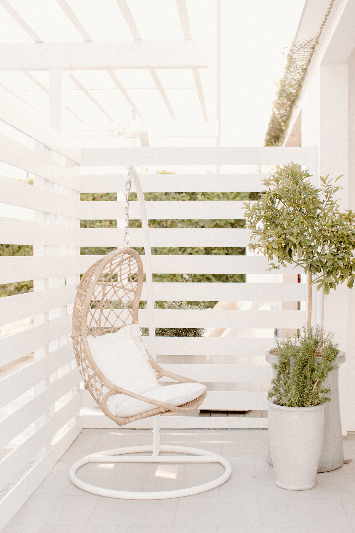 hanging woven chair with plants and white fence