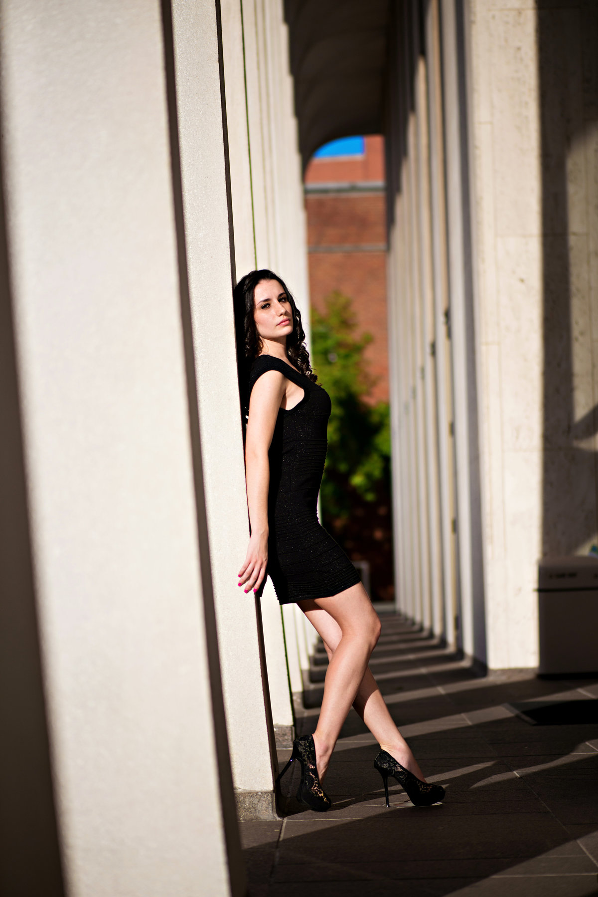 A model leans agains pillars letting the sun kiss her skin.