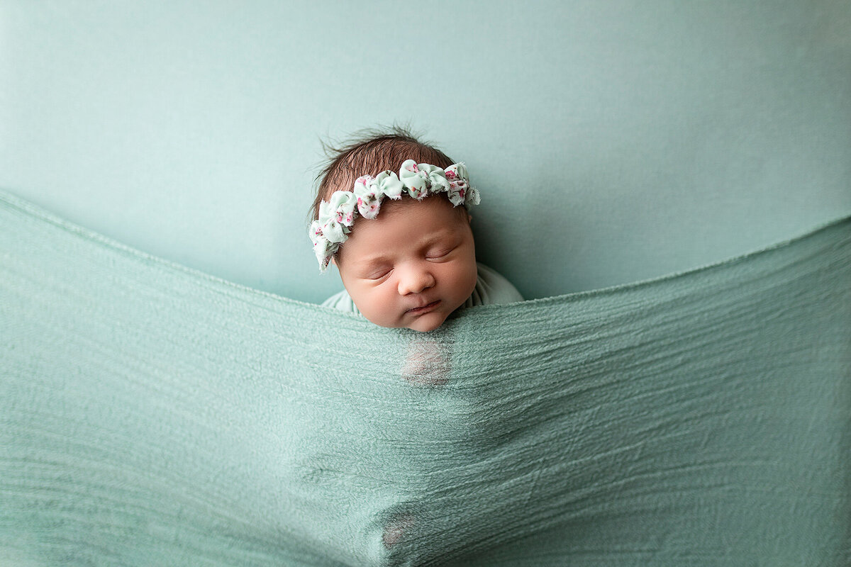 Baby girl sleeping on eggshell blue during her newborn session.