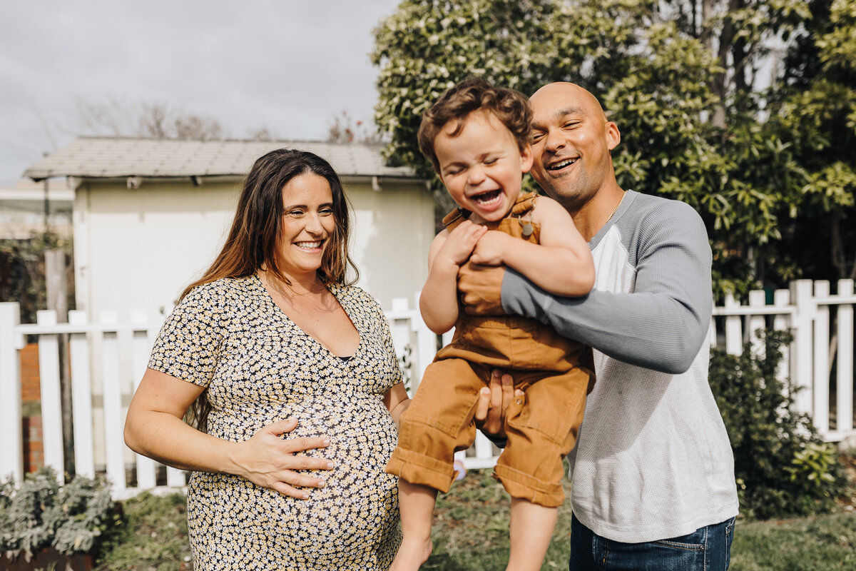 Laughing toddler with pregnant mom & dad Emily Woodall Photography