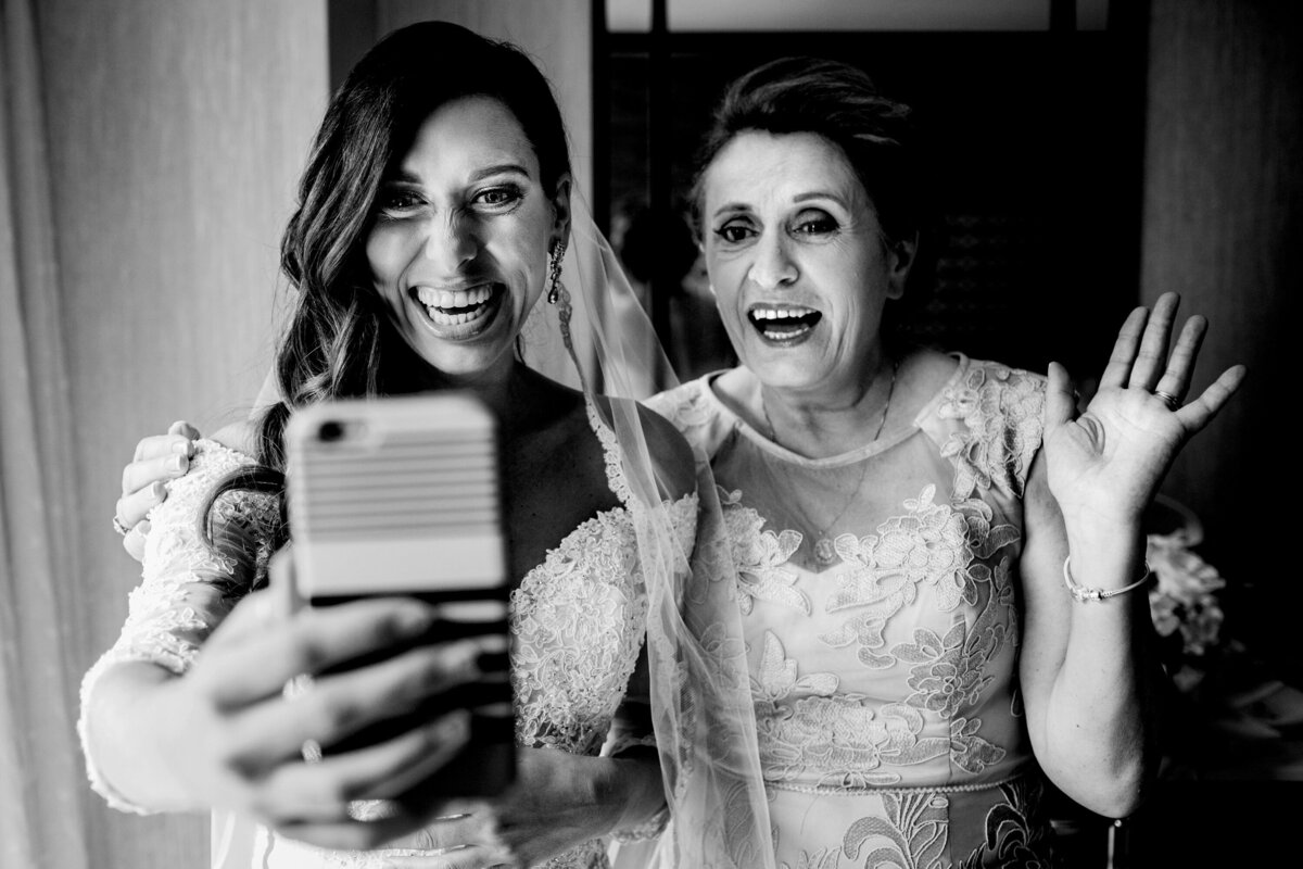 A bride laughs with her mom while talking to relatives abroad during a Chicago wedding.