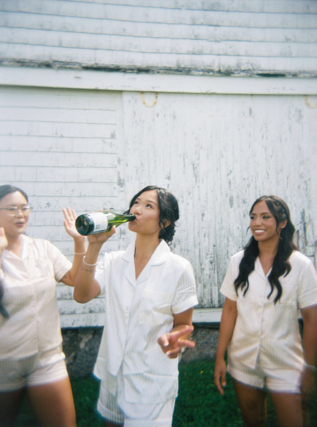 Bride drinking champagne from bottle with bridesmaids at  Woodburn Ridge Wedding, Nova Scotia
