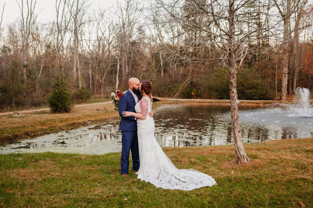 photo of bride and groom kissing in front of a pond with a fountain