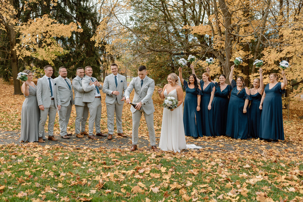 groom pops champagne as wedding party cheers